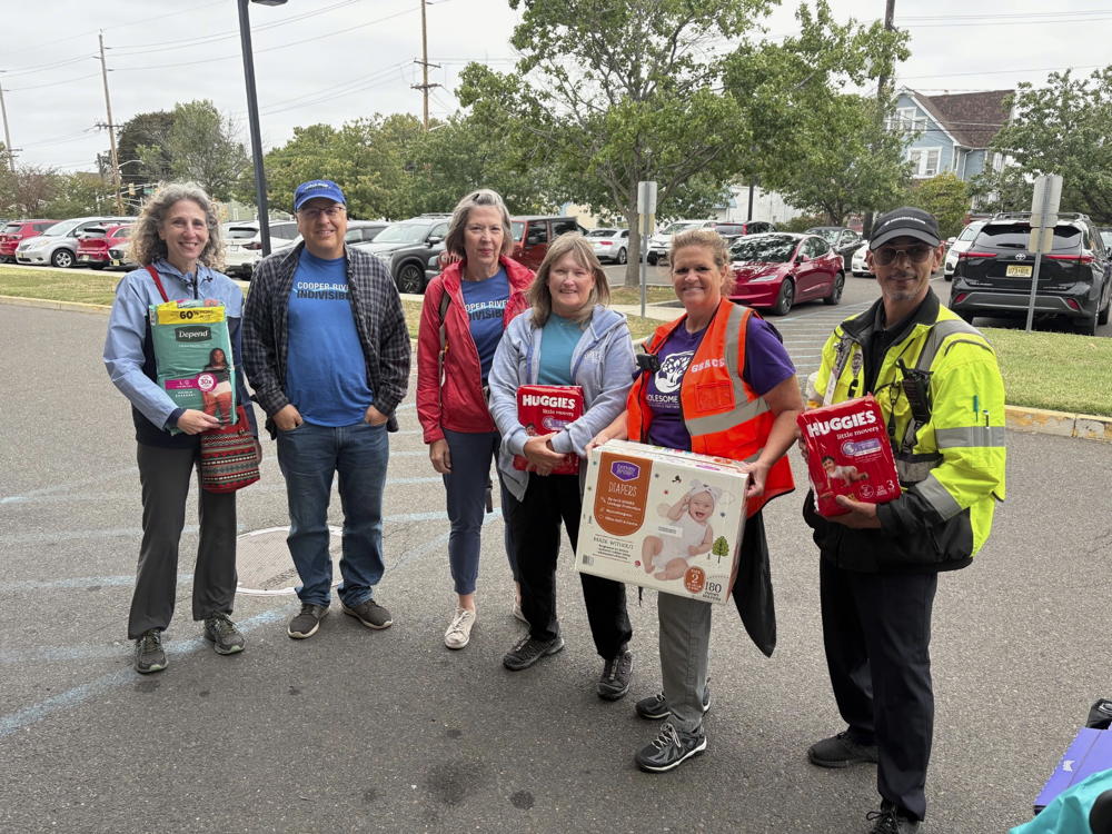 Six people stand in the school parking lot holding a few of the items that were collected for the mutual aid drive