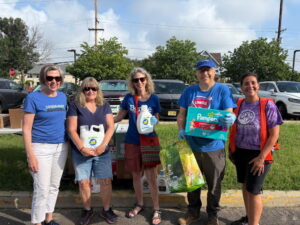 Five people pose in front of the items collected and delivered to Wholesome Riches in Camden