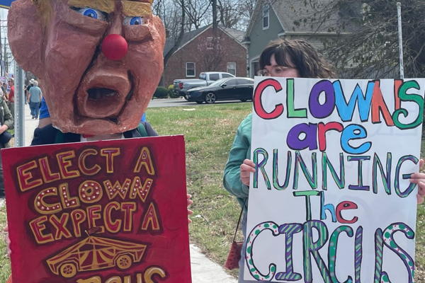 Two out of 1000+ protestors from today. One is dressed as a mockup of Trump with a sign that says "Elect a Clown Expect a Circus"