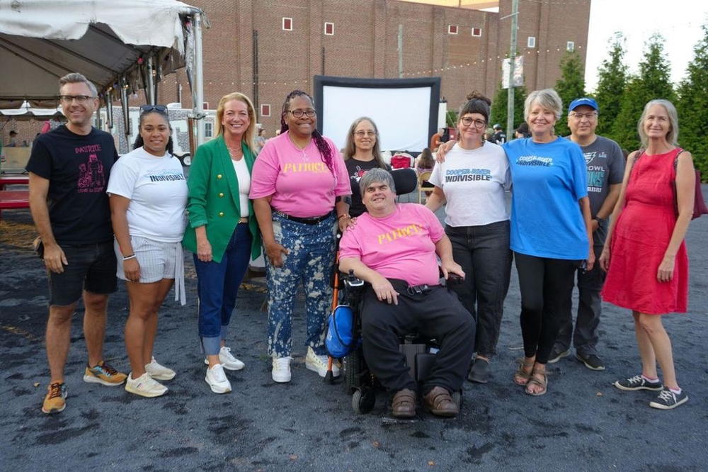 A group of people stand in Haddon Square for a picture. In the background is the side wall of the old Westmont Movie Theatre.