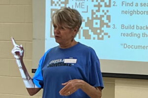 A person is teaching a class with a QR code in the background.