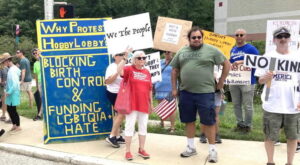 A group of people protesting in front of a target store. They hold signs and flags