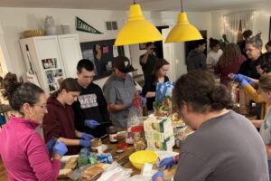 A group of people stand around a kitchen island making sandwiches for the Cathedral Kitchen in Camden