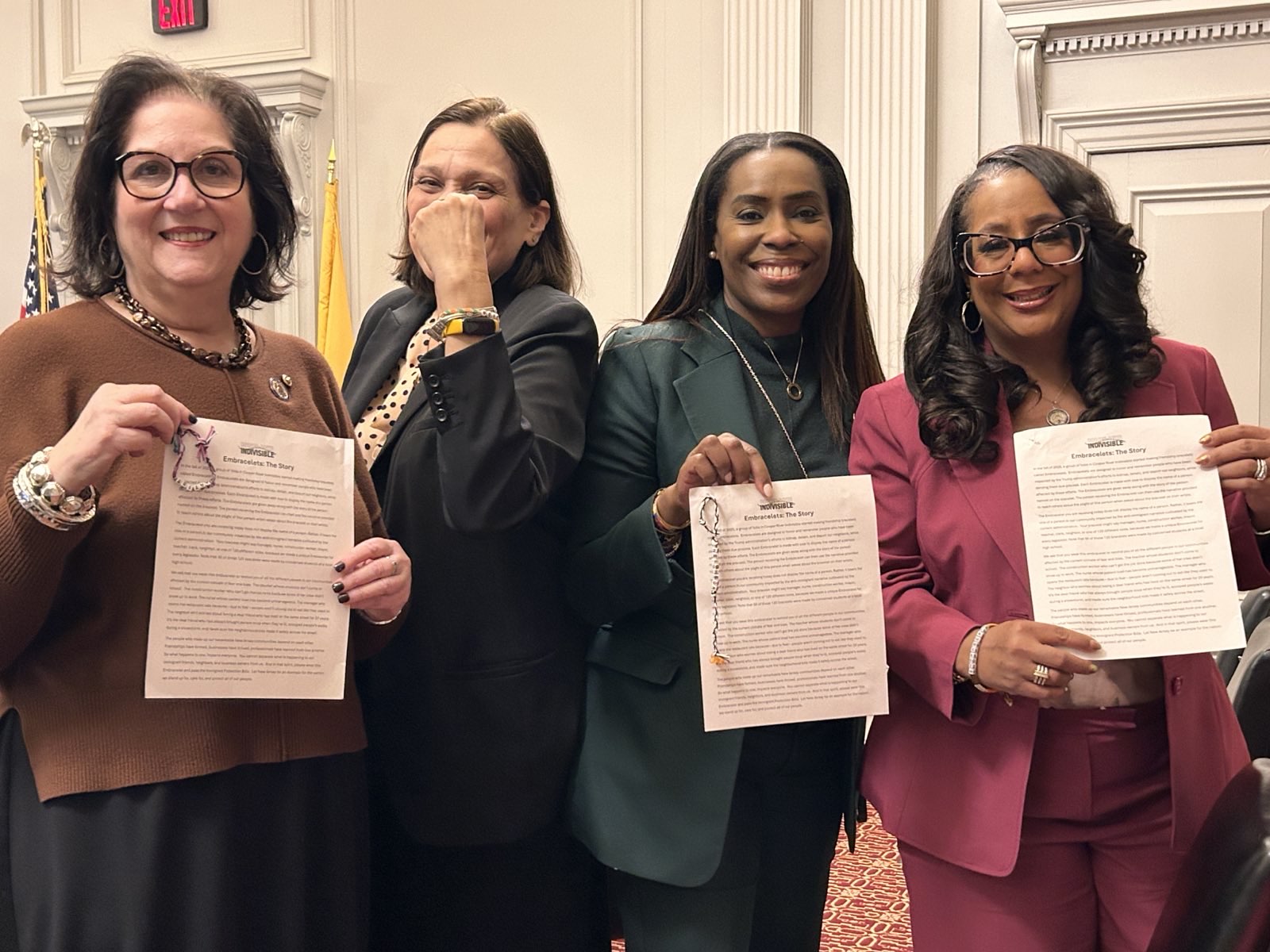 Four lawmakers pose with their embracelets on the floor of the state house