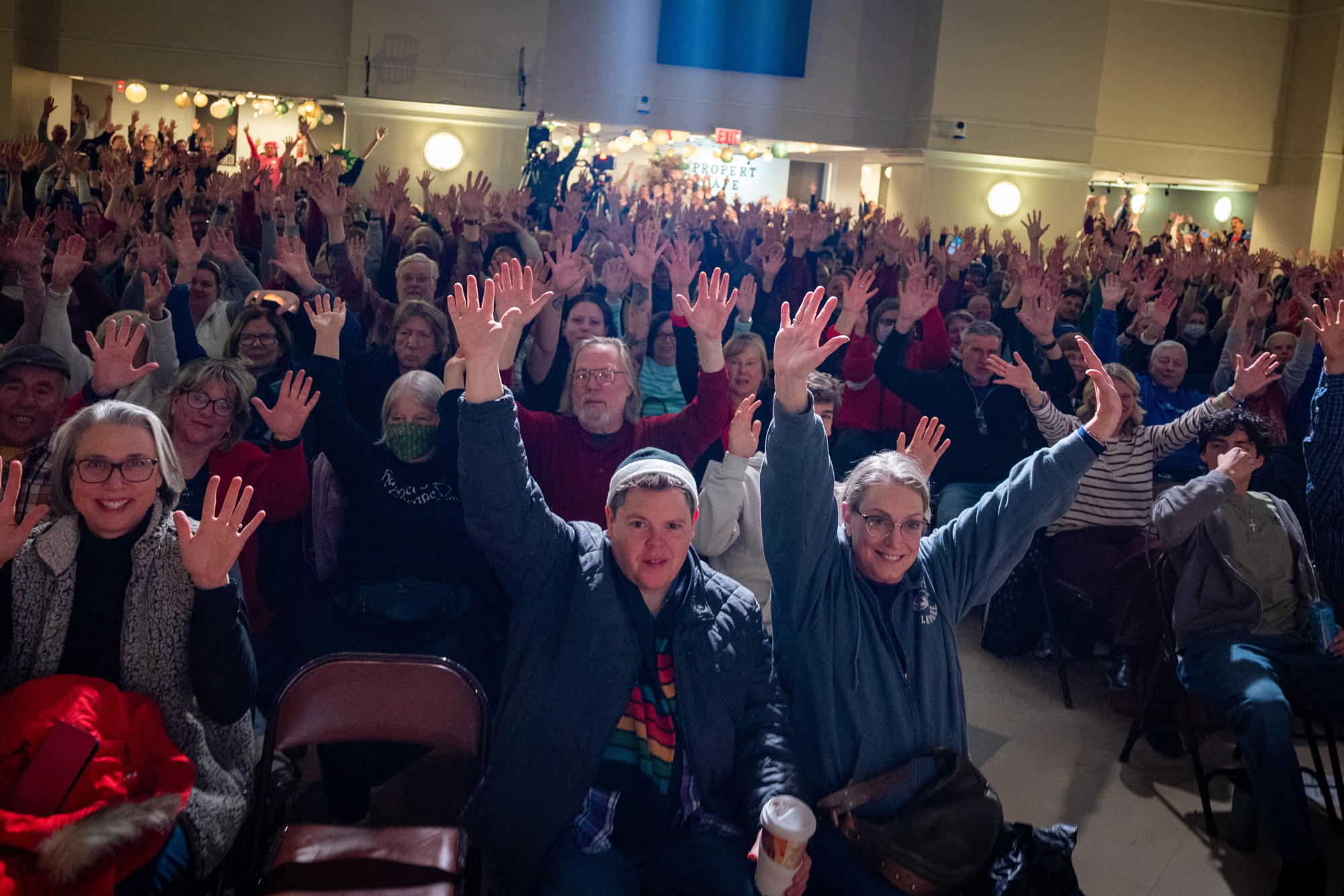 A picture taken from the stage at Haddonfield Methodist Church.  All people in the crowed are all raising their hands