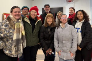 A group of people bundled in their winter coats pose for a picture at the food pantry at LUCY.