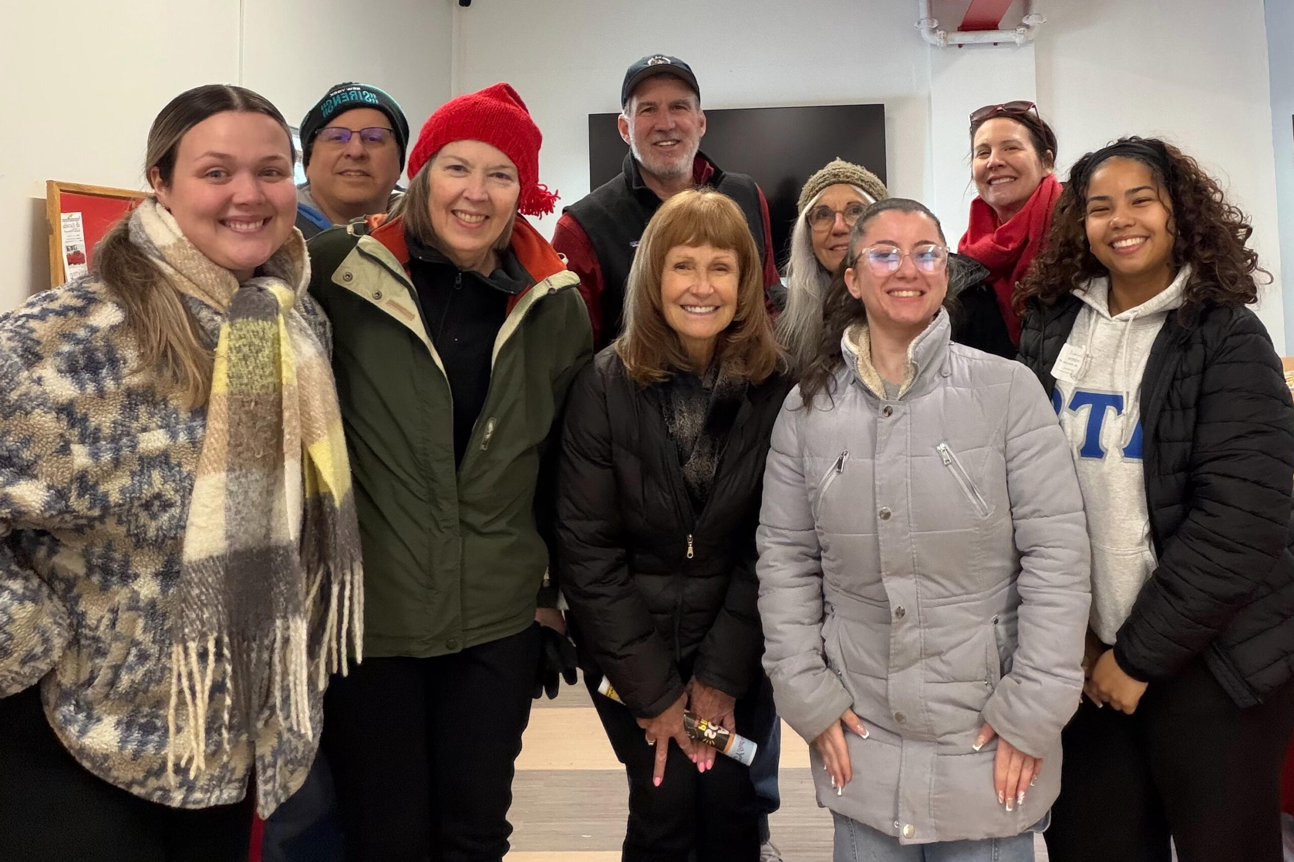 A group of people bundled in their winter coats pose for a picture at the food pantry at LUCY.