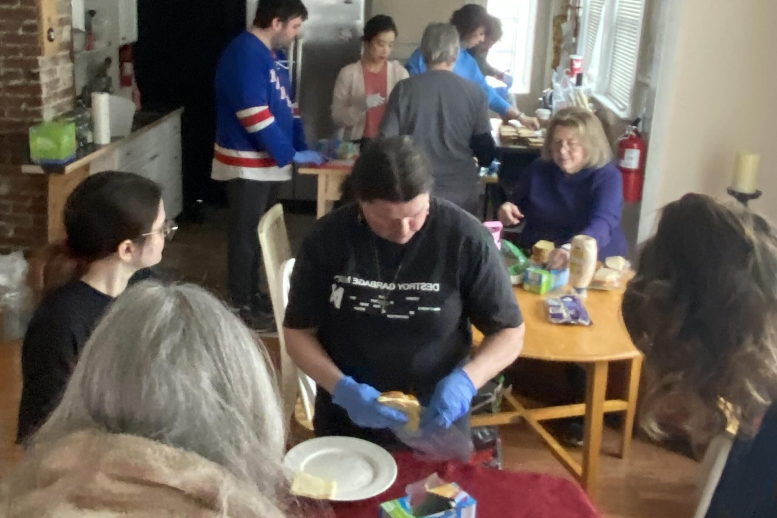 About a dozen people occupy different locations in the kitchen making sandwiches for Cathedral Kitchen