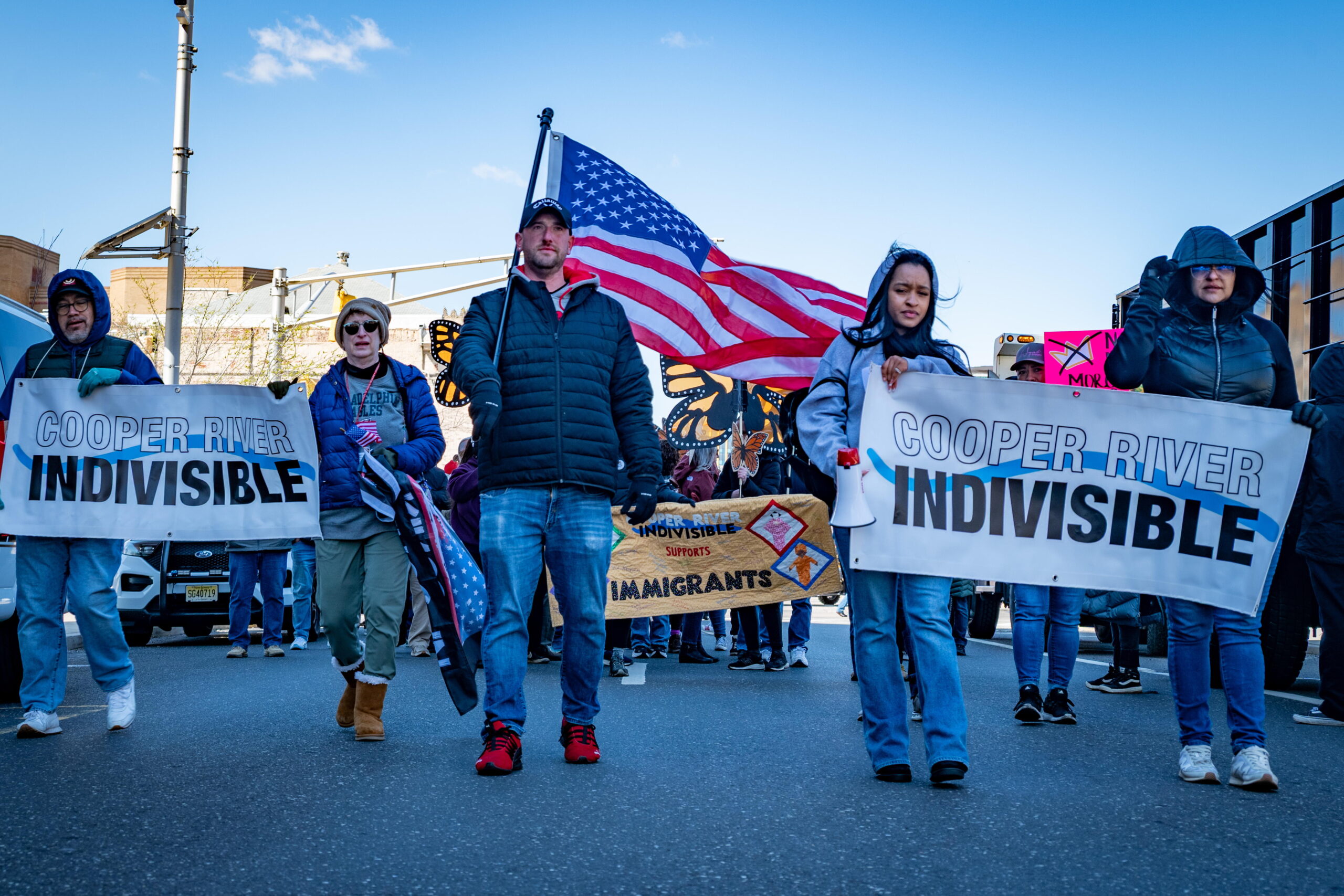 Picture taken from ground level.  On each side are two people holding CRI banners. and in the middle is CRI Guy holding an American Flag
