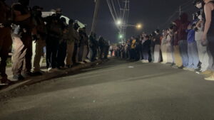 A night picture taken from ground level. On the left is a line of police and on the right is a line of protestors